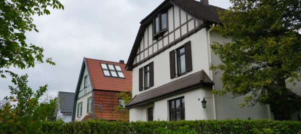 Several houses with green hedges under a cloudy sky